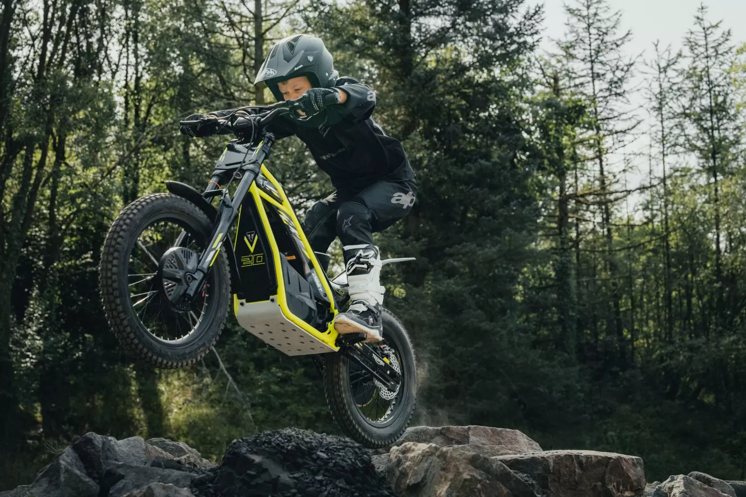 Triumph TXP-20 electric dirt bike jumping over rocky trail section