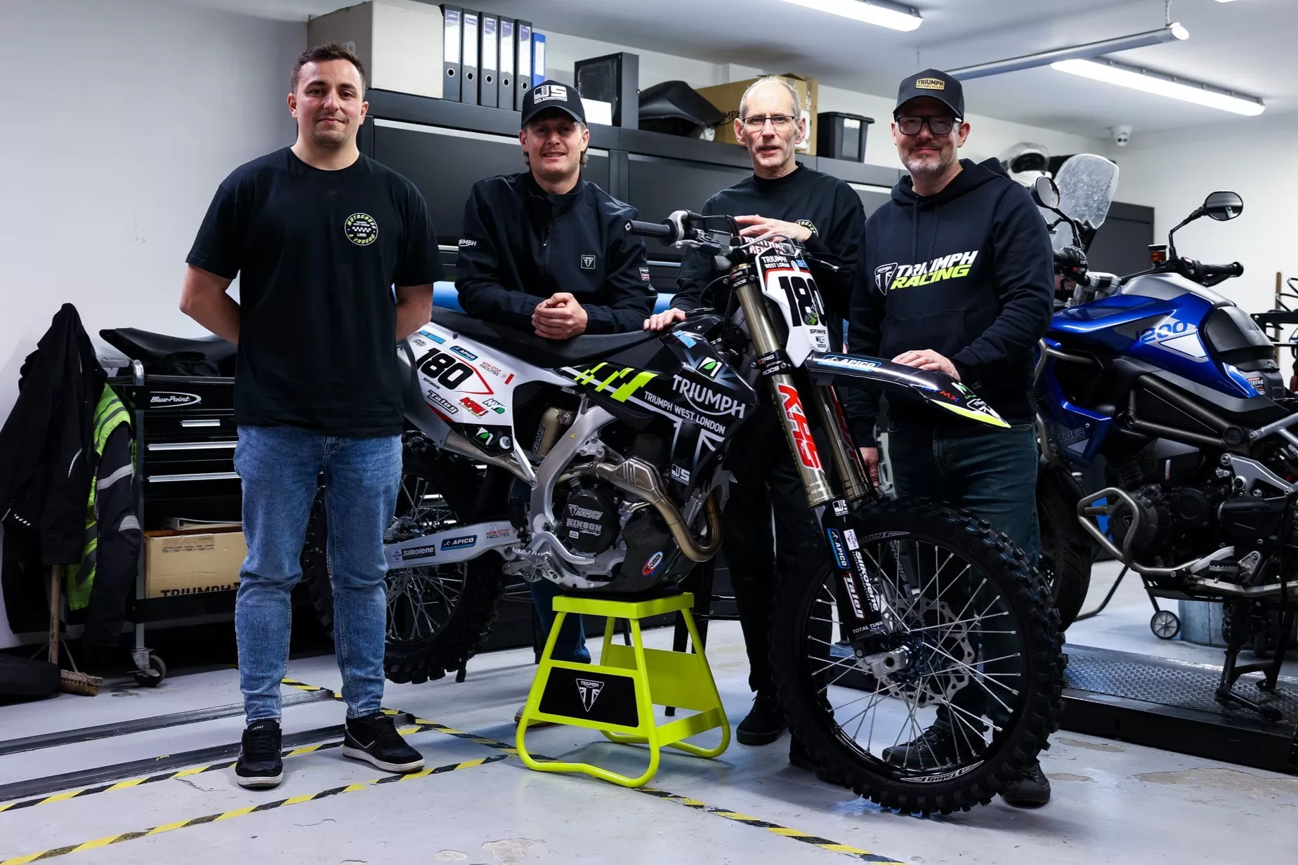 Josh Spinks and the Triumph West London team with the TF 450-RC in the workshop, celebrating the official announcement of their racing partnership.