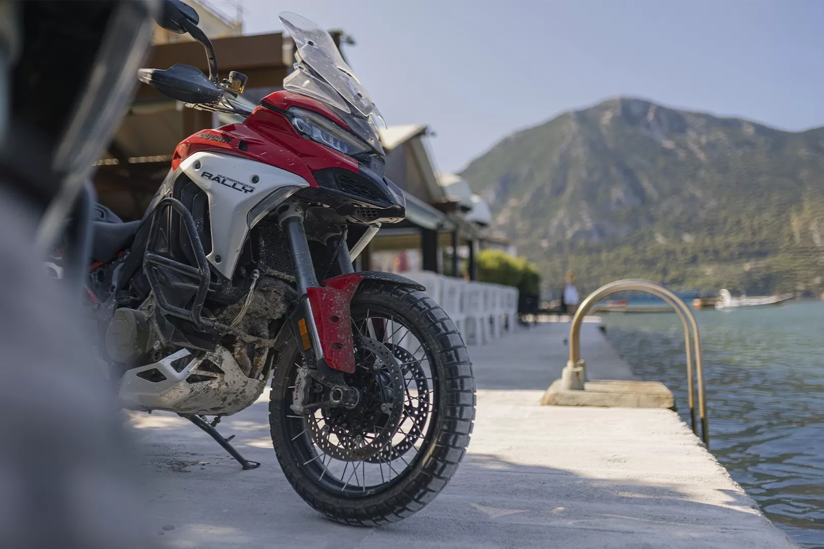 Front view of the new Ducati Multistrada V4 Rally parked near water with mountains in the background.