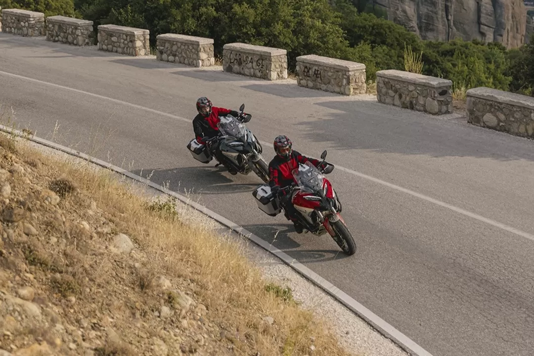 Two Ducati Multistrada V4 Rally motorcycles riding through winding mountain roads with panoramic views.
